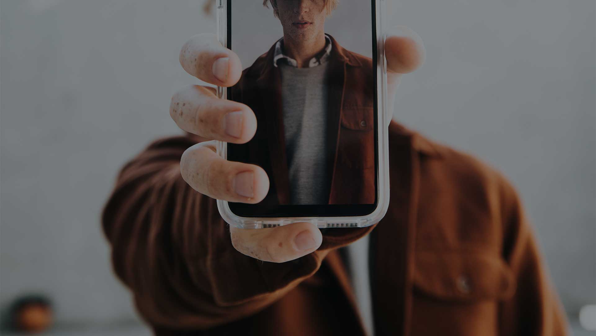Main d'un homme tendant un smartphone de face.